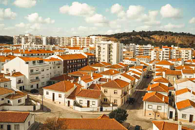 Bird's-eye view of Residential Costa da Caparica, featuring a mix of high-rises, residential areas, and open spaces against a sunny backdrop.